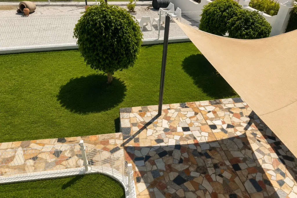 Zona exterior de descanso y sombra en Marbella Dog Club con césped natural y espacios seguros para perros.